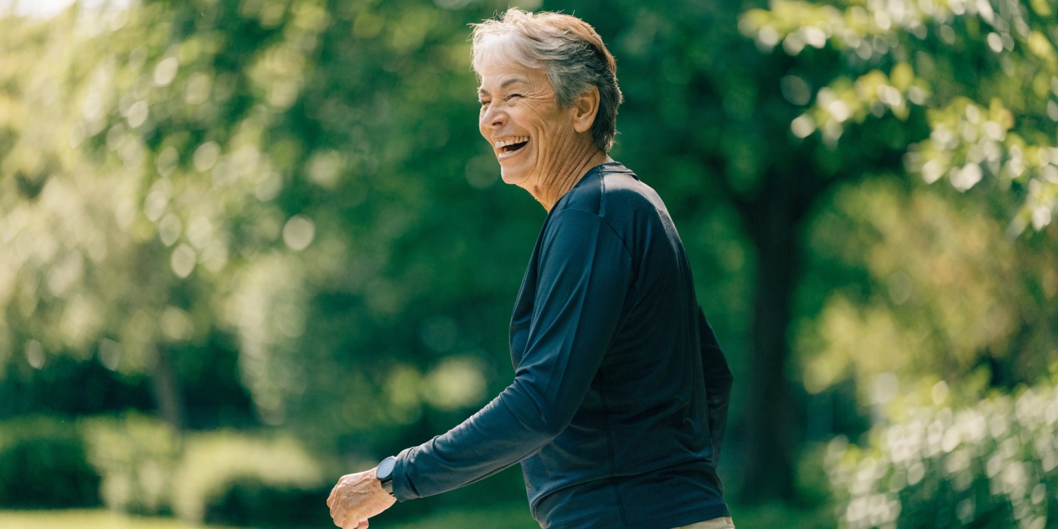Donna anziana attiva e sorridente che cammina all'aperto, longevita e healthspan